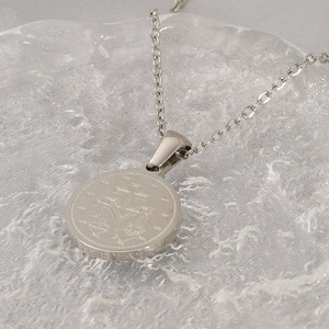 Silver Miraculous Medal necklace with religious coin pendant on a textured glass surface