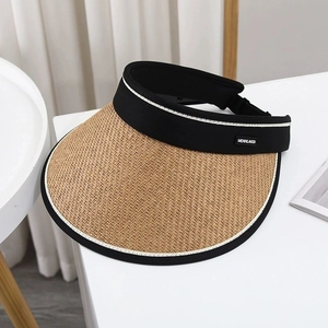 Detail of straw sun hat featuring a black fabric headband and branded metal logo plate