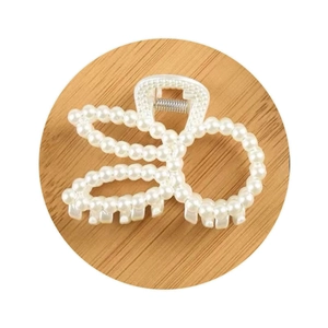 Elegant large pearl claw clip for women featuring a bow-shaped design on a wood tray