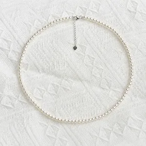 Classic round pearl necklace with S925 sterling silver heart clasp on white fabric