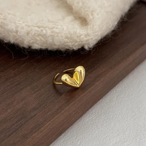 Macro shot of gold heart ring with polished finish on wooden and knit background