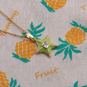 Close-up of gold star pendant necklace with green enamel and square crystal inlay