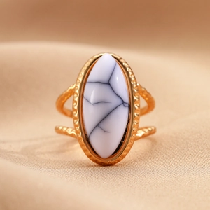 Detalle macro de anillo vintage dorado con piedra ovalada blanca y bordes martillados