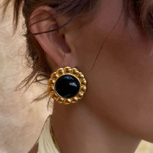 Close-up of vintage scalloped gold earrings with black agate inlay on model ear
