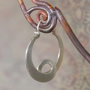 Orecchini a spirale geometrica scavata in argento vintage appesi a un supporto decorativo