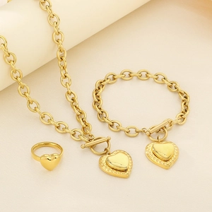 Detailed view of golden heart jewelry set with necklace bracelet and ring on beige surface