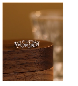 Macro shot of silver hollow heart ring with sparkling zircons on wooden base