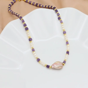 Baroque pearl and amethyst necklace on a white ceramic tray with champagne satin background