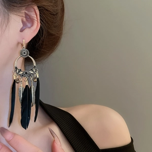 Détail de boucles d'oreilles bohèmes à pampilles en plumes avec métal bronze et perles noires