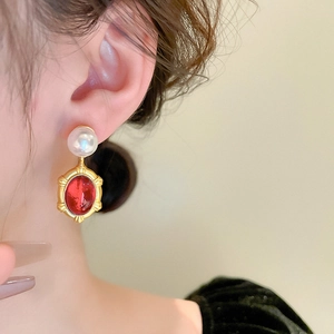 Close-up of vintage resin oval earrings with gold frames and white pearls worn by a model