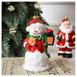 Detailed view of hand-painted snowman and Santa ornaments with gold string hanging on a tree