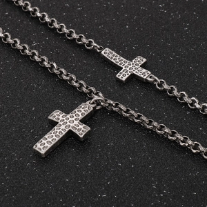 Close-up of vintage distressed steel cross pendants with hammered texture and woven chain