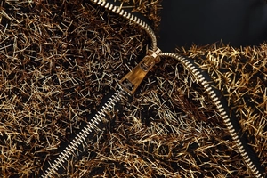 Detail of luxurious gold metallic fringe fabric with a high-quality silver metal zipper