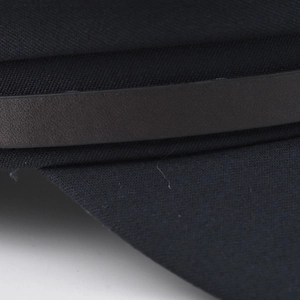 Gros plan détaillé du tissu en sergé noir et du bracelet en cuir sur le bonnet