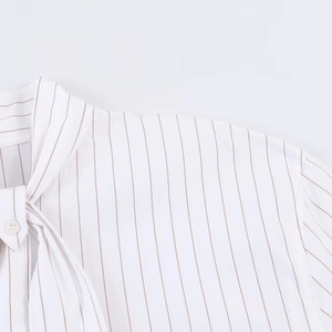 Detail of pinstripe poplin shirt showing tie-neck bow and white button fastening