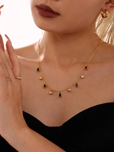 Detail of 18k gold plated drop necklace with black gems and white zircon on model