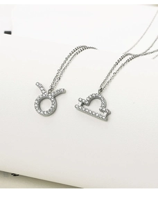 Macro detail of silver Taurus and Libra zodiac pendants with zircon pavé setting