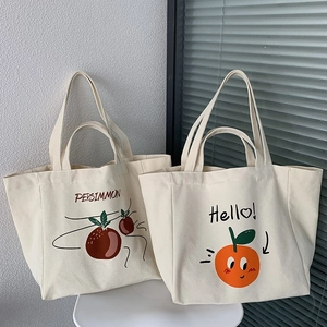 Detail of cream canvas tote bags featuring persimmon and orange illustrations on a chair