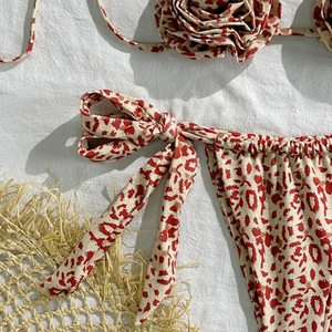 Detail of red leopard print bikini with 3D floral accents and side-tie ribbed bottoms