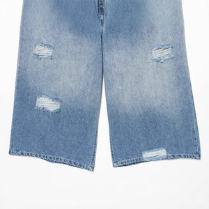Jean en denim délavé bleu avec déchirures stylées sur un fond blanc épuré