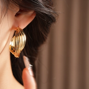 Close-up of golden multi-layered twisted hoop earring on model showing metallic luster