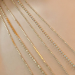 Detailansicht goldener Box-Ketten und funkelnder Strass-Tennis-Ketten auf Seide