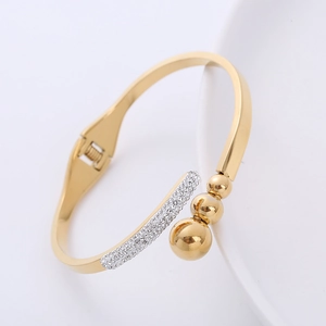 Bracciale rigido dorato lucido con pavé di zirconi bianchi e perline d'oro graduate