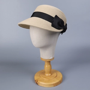 Dettaglio del cappello di paglia beige con nastro nero largo e fiocco laterale raffinato