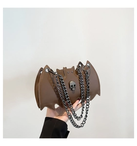 Detail of bat-shaped leather bag with skull hardware and layered metal chains
