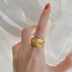 Detail of a vintage golden signet ring with embossed lion texture worn on finger