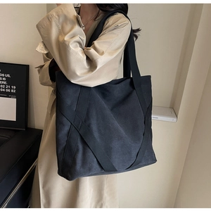Detail of a large black canvas tote bag with unique cross-ribbon reinforcement on the side
