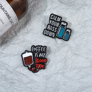 Détail de pins en émail avec slogan et texture pailletée sur fond gris texturé