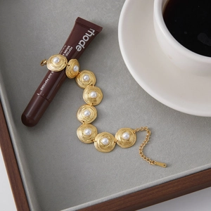 Detail of 18K gold-plated bracelet with spiral round links and white pearls
