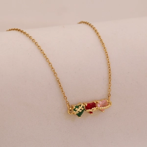 Close-up of golden necklace with green, red and pink heart pendants on beige background