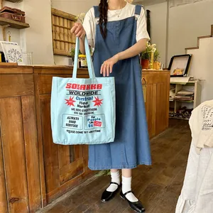 Detail of light blue canvas tote bag with retro graphic print and large capacity handles