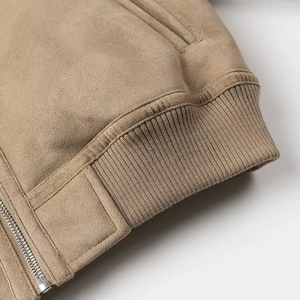 Gros plan sur la manche d'une veste en daim kaki avec poignets côtelés et zip métallique