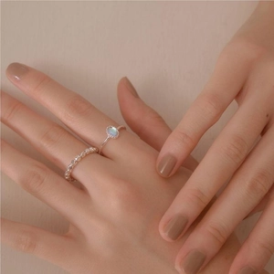 Detailed view of two minimalist 925 sterling silver rings with blue gemstone on model hand