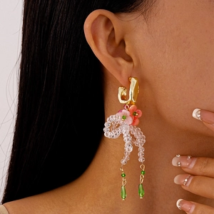 Detail of floral resin earrings with beaded bow tassels and green teardrop pendants