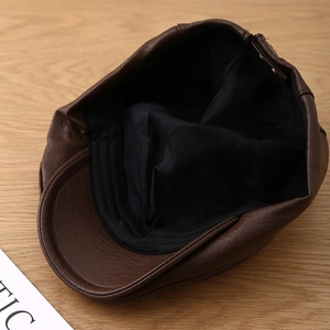 Detailed macro view of deep brown leather flat cap with smooth inner lining and metal buckle