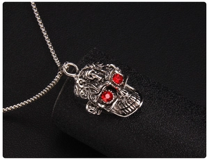 Gros plan d'un pendentif tête de mort punk avec yeux en gemme rouge et métal gravé