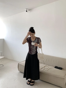 Detail of a purple tie-dye V-neck T-shirt paired with a black high-waisted long skirt
