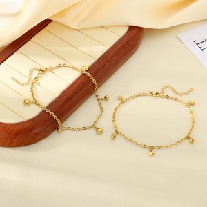 Detail of 18K gold plated anklets with beads and charms on a wooden jewelry display