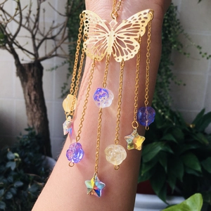 Close-up of golden butterfly suncatcher with colorful floral accents and starry pendants