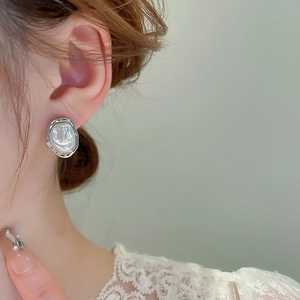 Close-up of a model wearing silver irregular baroque pearl earrings with metallic frame
