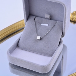 Detailed view of silver titanium steel square pendant necklace in a velvet jewelry box