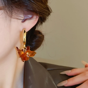 Close-up of elegant Maillard flower earrings with amber resin petals and golden hoops