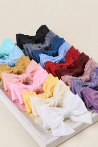 Détail de nœuds à cheveux en tissu à bords volantés de diverses couleurs sur bois blanc