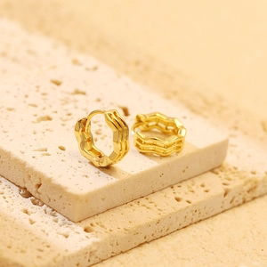 Detailed view of gold S925 silver wavy hoop earrings on textured stone display