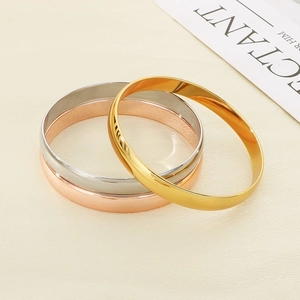 Close-up of gold silver and rose gold polished stainless steel bangle set for women