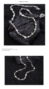 Detailed views of silver heart and diamond linked necklace on textured black surface